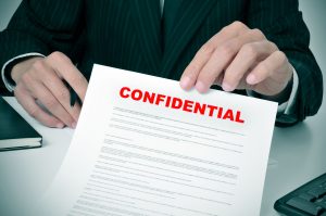 28255631 - a man wearing a suit showing a document with the text confidential written in it